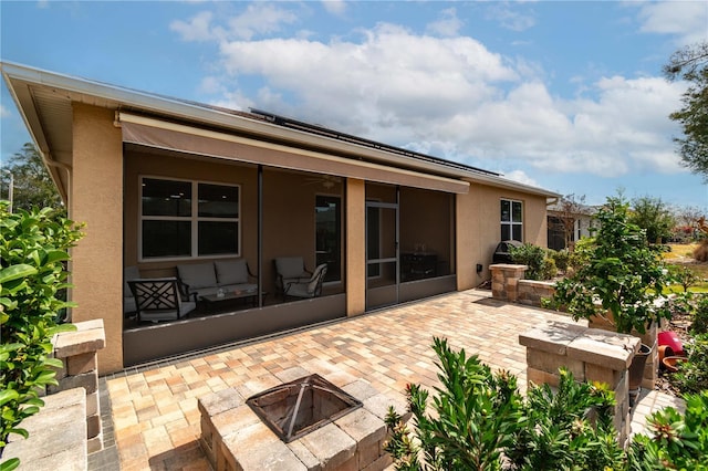 rear view of property featuring a fire pit, a sunroom, and a patio