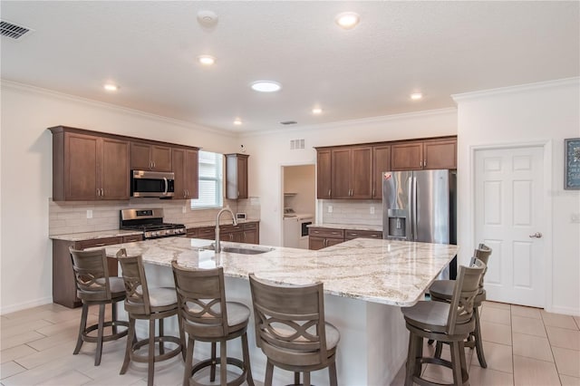 kitchen featuring a large island, sink, stainless steel appliances, and light stone countertops