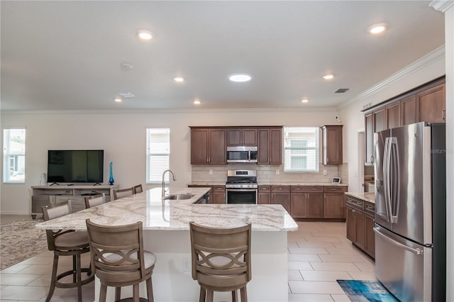 kitchen with stainless steel appliances, sink, a kitchen breakfast bar, and a large island with sink