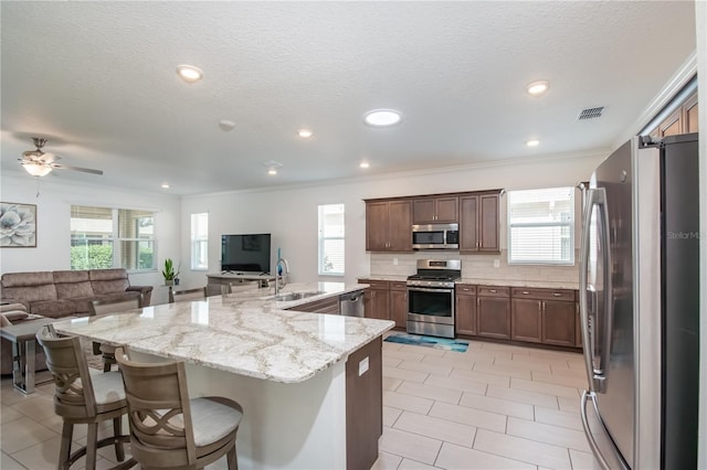 kitchen with tasteful backsplash, sink, a breakfast bar area, light stone counters, and stainless steel appliances