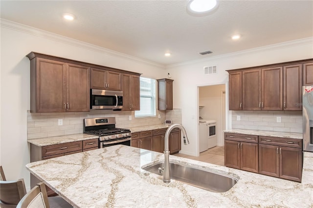 kitchen with sink, backsplash, stainless steel appliances, a kitchen breakfast bar, and light stone counters