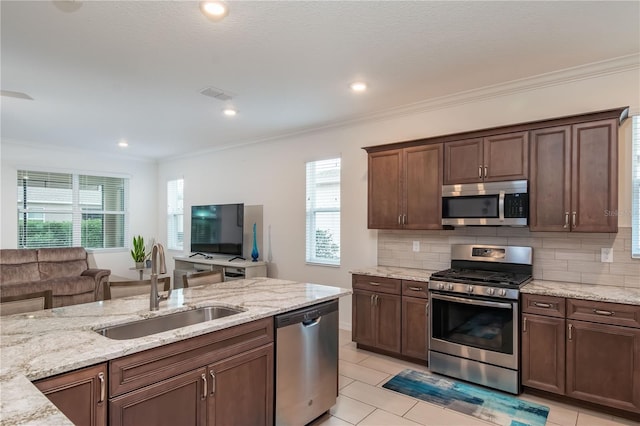 kitchen with sink, crown molding, appliances with stainless steel finishes, light stone countertops, and decorative backsplash