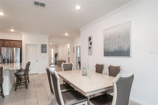 tiled dining area featuring ornamental molding and a textured ceiling