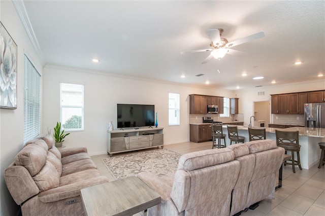 tiled living room featuring ceiling fan, ornamental molding, and sink