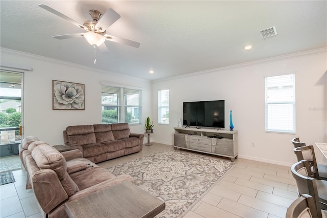 living room with light tile patterned flooring, ceiling fan, ornamental molding, and a textured ceiling