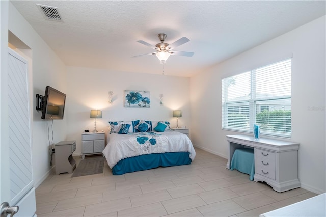 bedroom with ceiling fan and a textured ceiling