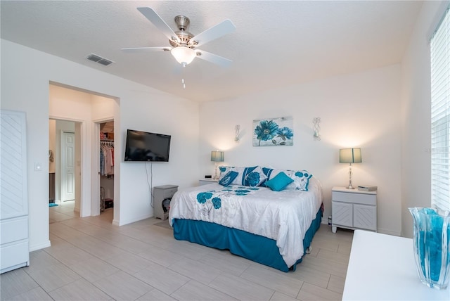 bedroom with a walk in closet, a textured ceiling, ceiling fan, and a closet