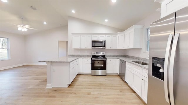 kitchen with white cabinetry, appliances with stainless steel finishes, kitchen peninsula, and light stone counters