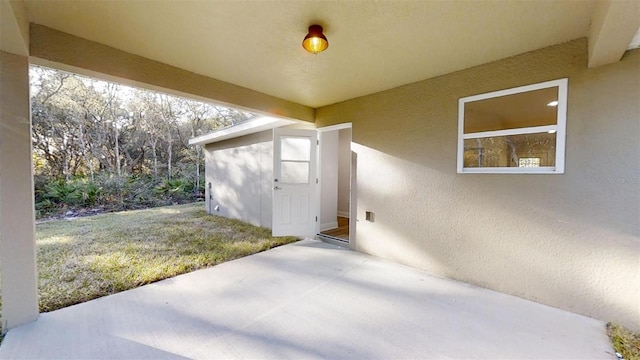 property entrance with a lawn and a patio area