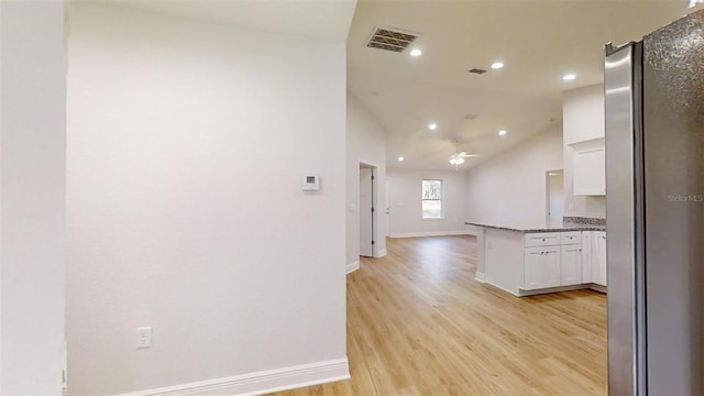 kitchen with stainless steel fridge, white cabinetry, light hardwood / wood-style floors, vaulted ceiling, and kitchen peninsula