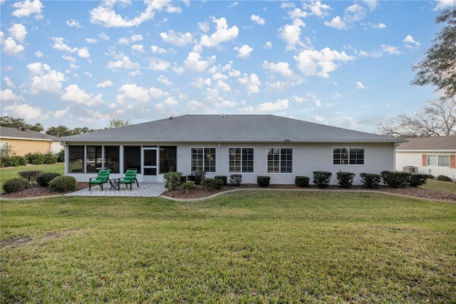 rear view of property featuring a yard, a sunroom, and a patio