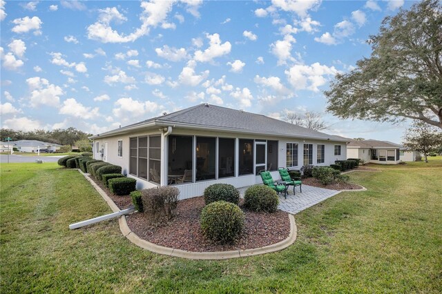 rear view of property with a yard, a patio area, and a sunroom