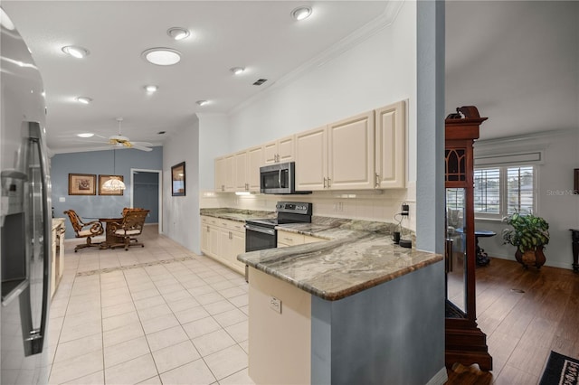 kitchen featuring stainless steel appliances, crown molding, light stone countertops, and cream cabinets