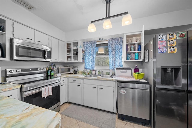 kitchen with appliances with stainless steel finishes, decorative light fixtures, white cabinetry, sink, and light tile patterned floors