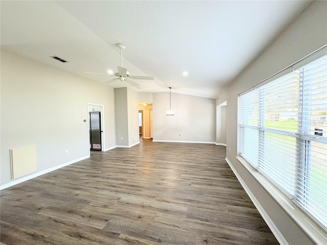 empty room with a textured ceiling, vaulted ceiling, dark hardwood / wood-style floors, and ceiling fan