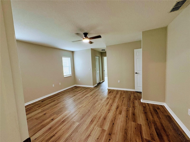 empty room featuring ceiling fan, a textured ceiling, and light hardwood / wood-style floors