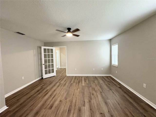 empty room with ceiling fan, wood-type flooring, and a textured ceiling