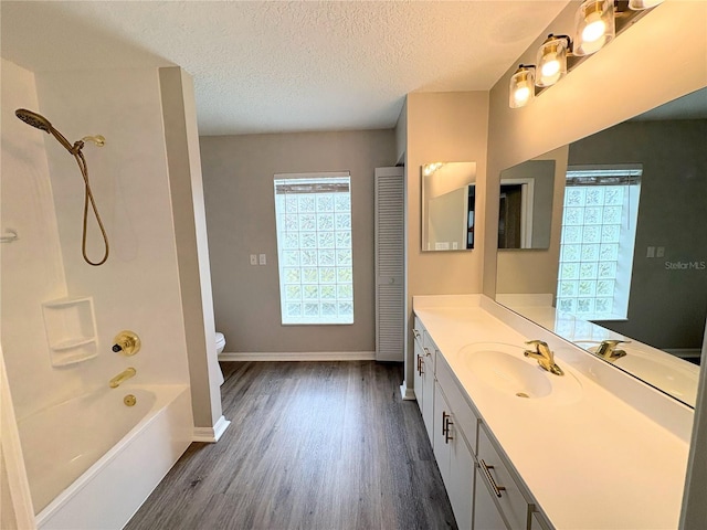 full bathroom with shower / washtub combination, hardwood / wood-style floors, vanity, toilet, and a textured ceiling