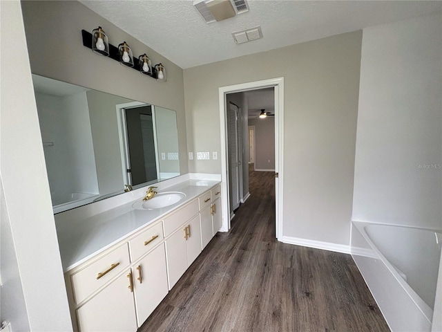 bathroom featuring a washtub, vanity, wood-type flooring, and a textured ceiling