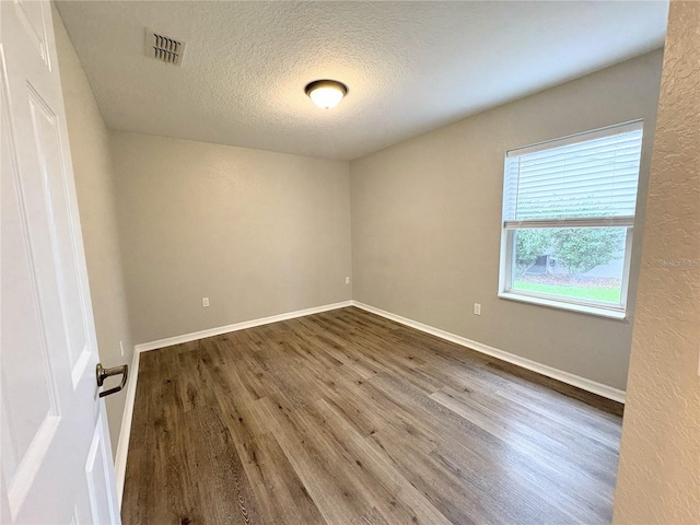 unfurnished room with wood-type flooring and a textured ceiling