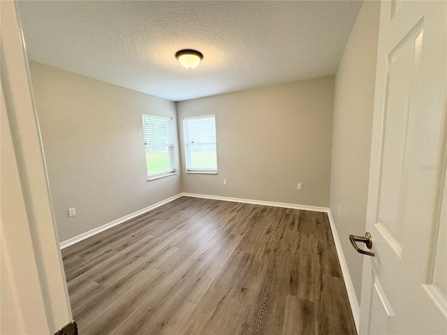 empty room featuring a textured ceiling and dark hardwood / wood-style flooring