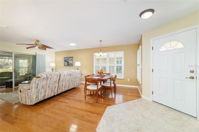 foyer with baseboards, ceiling fan with notable chandelier, and light wood-style floors