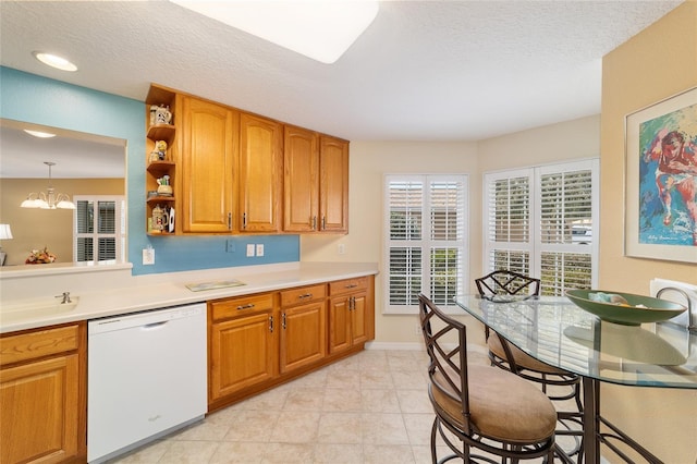 kitchen with dishwasher, light countertops, brown cabinetry, and a sink