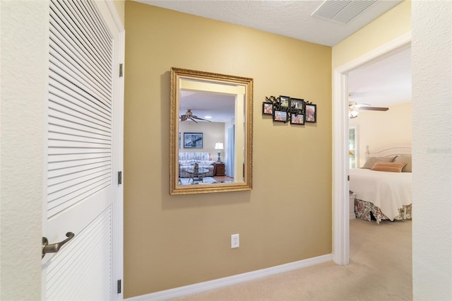 corridor featuring carpet flooring, visible vents, and baseboards