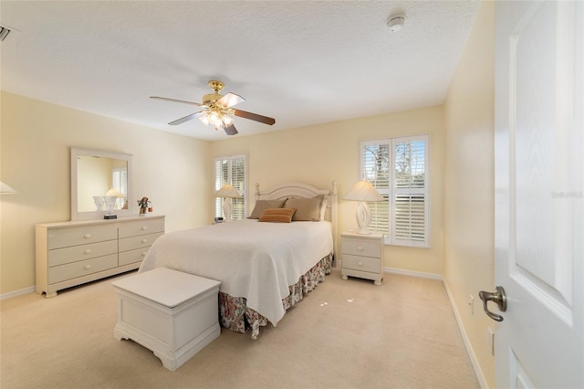 bedroom featuring light carpet, a textured ceiling, and baseboards