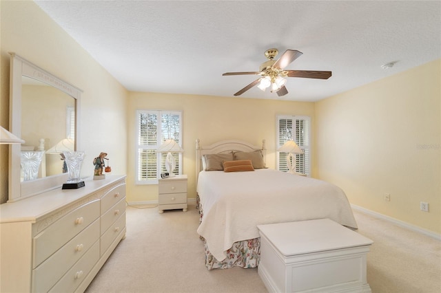 bedroom featuring a textured ceiling, baseboards, a ceiling fan, and light colored carpet