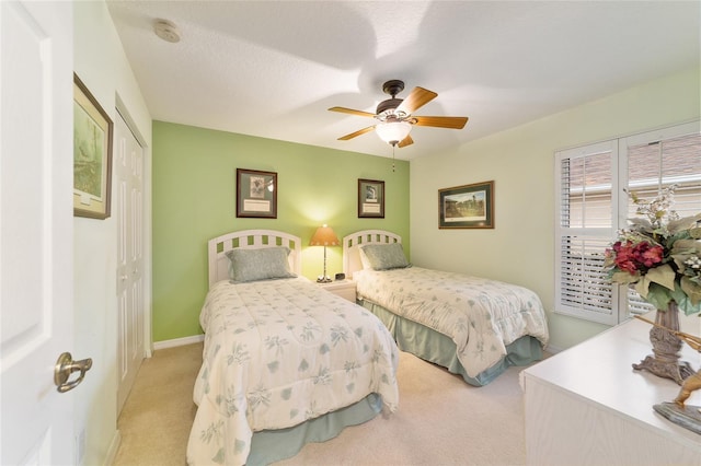 bedroom with light carpet, ceiling fan, a closet, and a textured ceiling