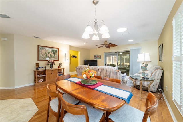 dining space with light wood-style floors, visible vents, baseboards, and ceiling fan with notable chandelier