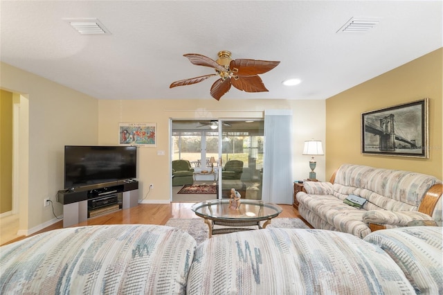 living area featuring a ceiling fan, wood finished floors, visible vents, and baseboards