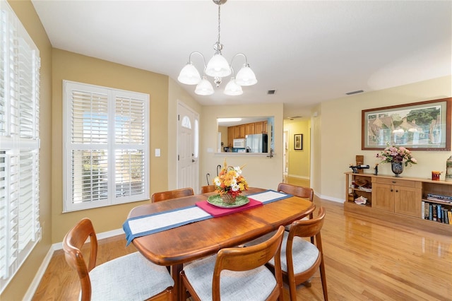 dining area with light wood-style floors, visible vents, and baseboards