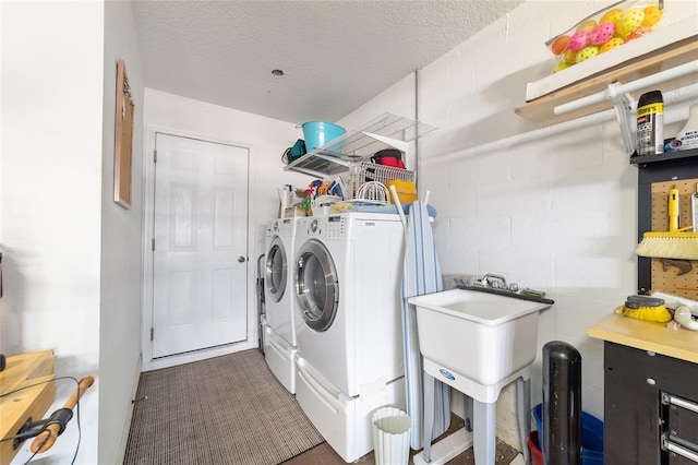 washroom with concrete block wall, laundry area, washer and clothes dryer, and a textured ceiling