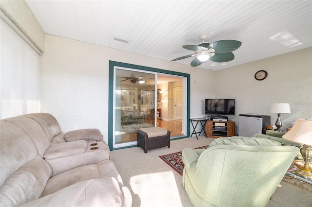 living room with a textured wall, carpet flooring, and ceiling fan