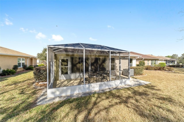 rear view of house featuring a lanai, central AC unit, a lawn, and a patio