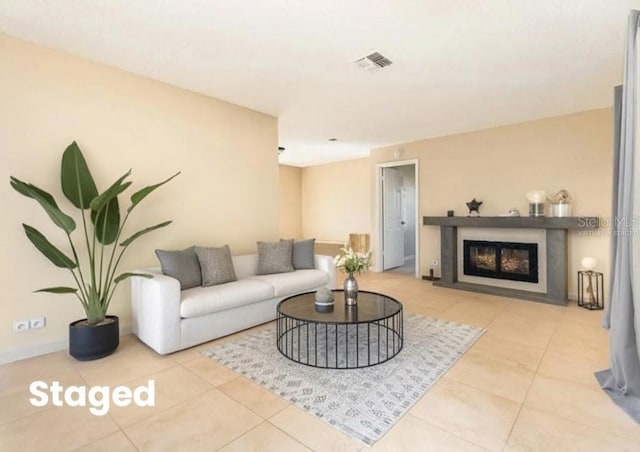 tiled living room with a glass covered fireplace, baseboards, and visible vents