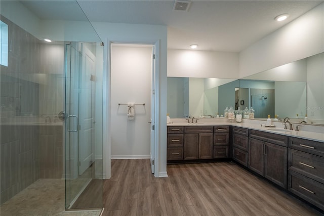 bathroom with hardwood / wood-style flooring, vanity, and a shower with door