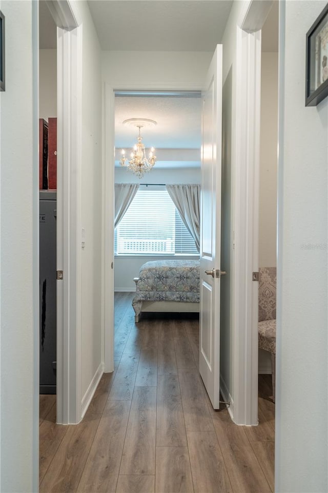 corridor featuring an inviting chandelier and light wood-type flooring