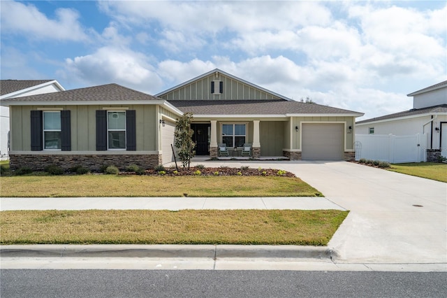 view of front of house with a garage, a front yard, and covered porch