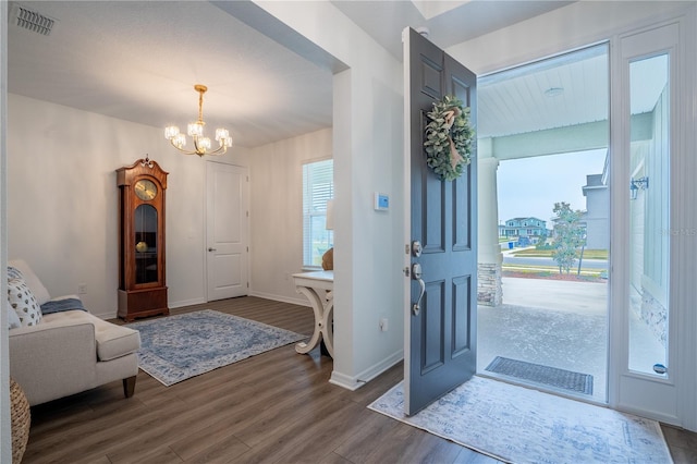 foyer with dark wood-type flooring, visible vents, baseboards, and an inviting chandelier
