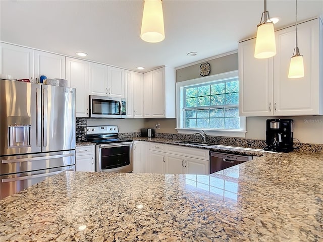 kitchen with stainless steel appliances, light stone countertops, pendant lighting, sink, and white cabinetry