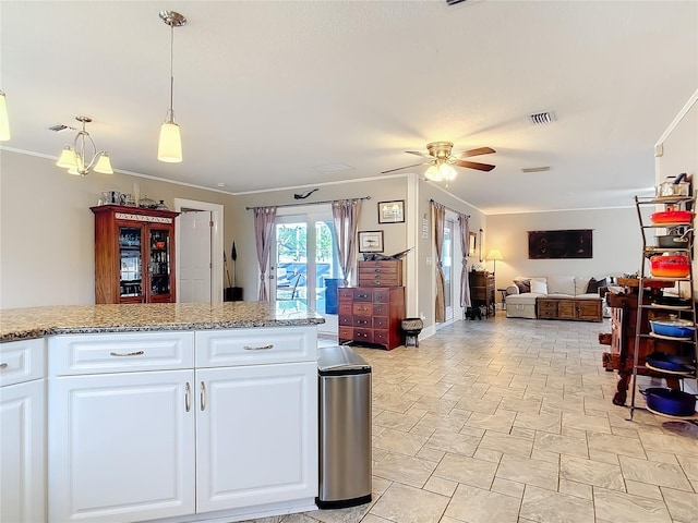 kitchen featuring white cabinetry, ornamental molding, light stone counters, ceiling fan, and pendant lighting