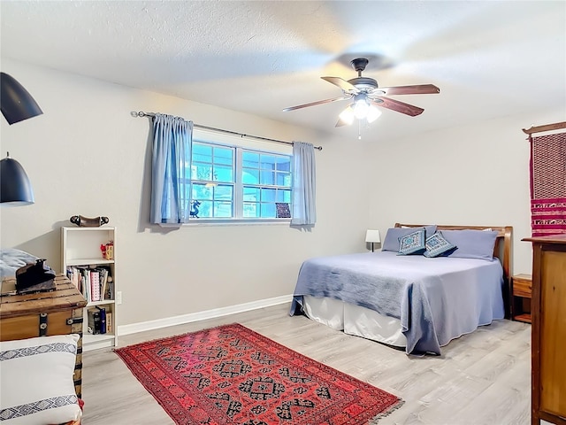 bedroom featuring light hardwood / wood-style flooring, ceiling fan, and a textured ceiling