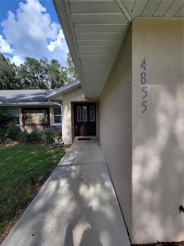 view of exterior entry featuring a yard and stucco siding