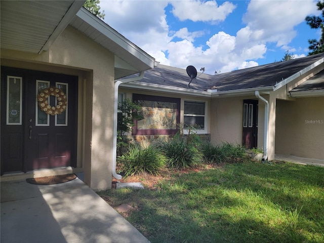 property entrance with stucco siding and a lawn