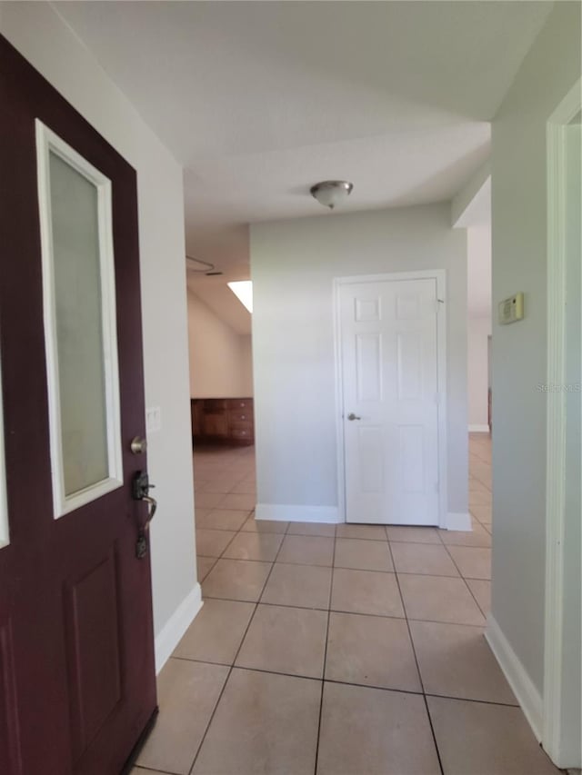 corridor with light tile patterned floors and baseboards