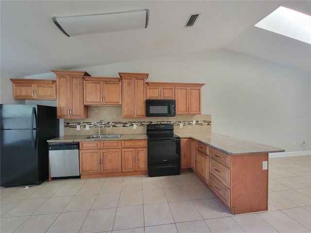 kitchen featuring visible vents, lofted ceiling with skylight, a peninsula, black appliances, and a sink