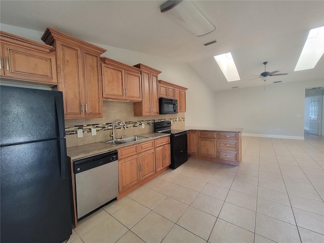 kitchen featuring brown cabinets, black appliances, a sink, vaulted ceiling with skylight, and decorative backsplash